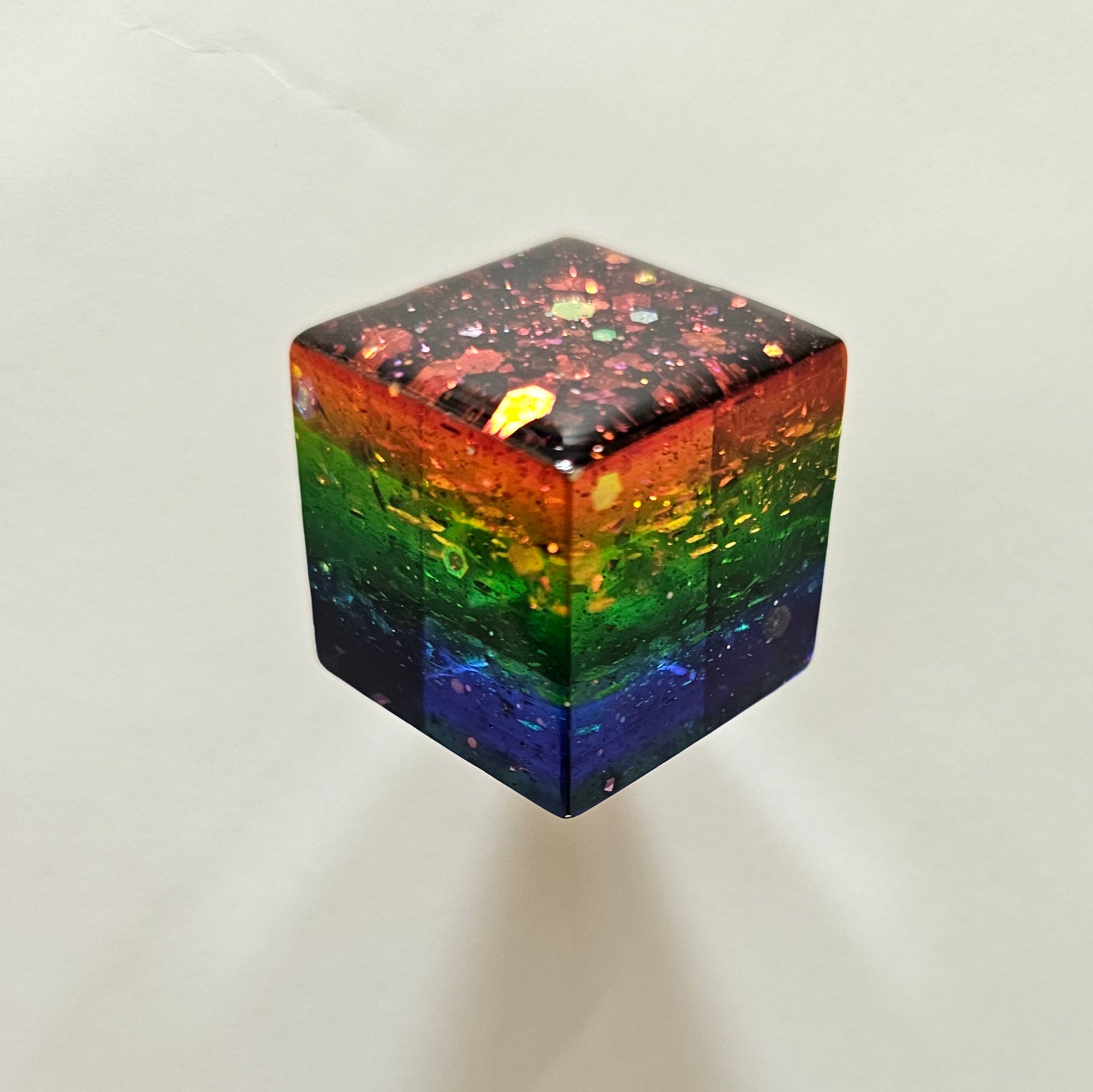 Rainbow-colored cube with a gradient from red to purple on a white background